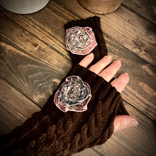Brown fingerless gloves with floral designs on a wooden surface