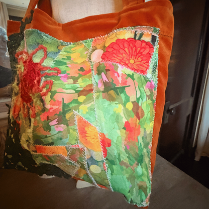A square patchwork tote bag with a vibrant green, red, and orange floral and koi fish pattern on the front, finished with a solid orange-brown velvet trim and shoulder strap.