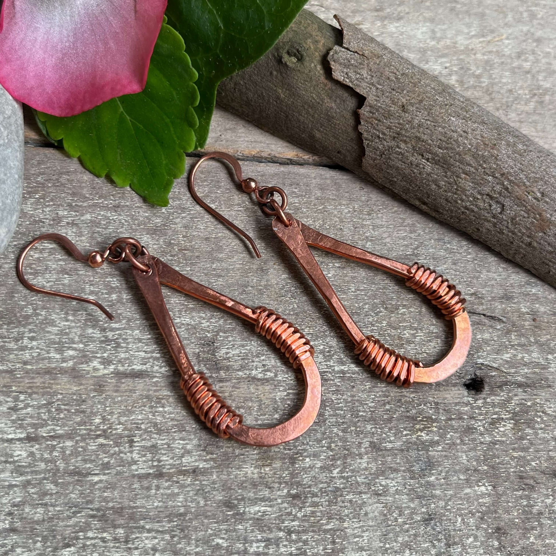 copper loop earrings displayed on wood with flower