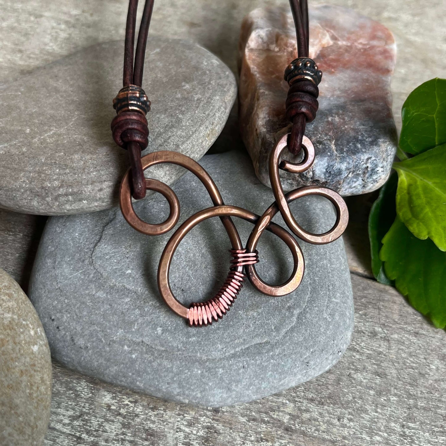 close up of copper swirl necklace on rock