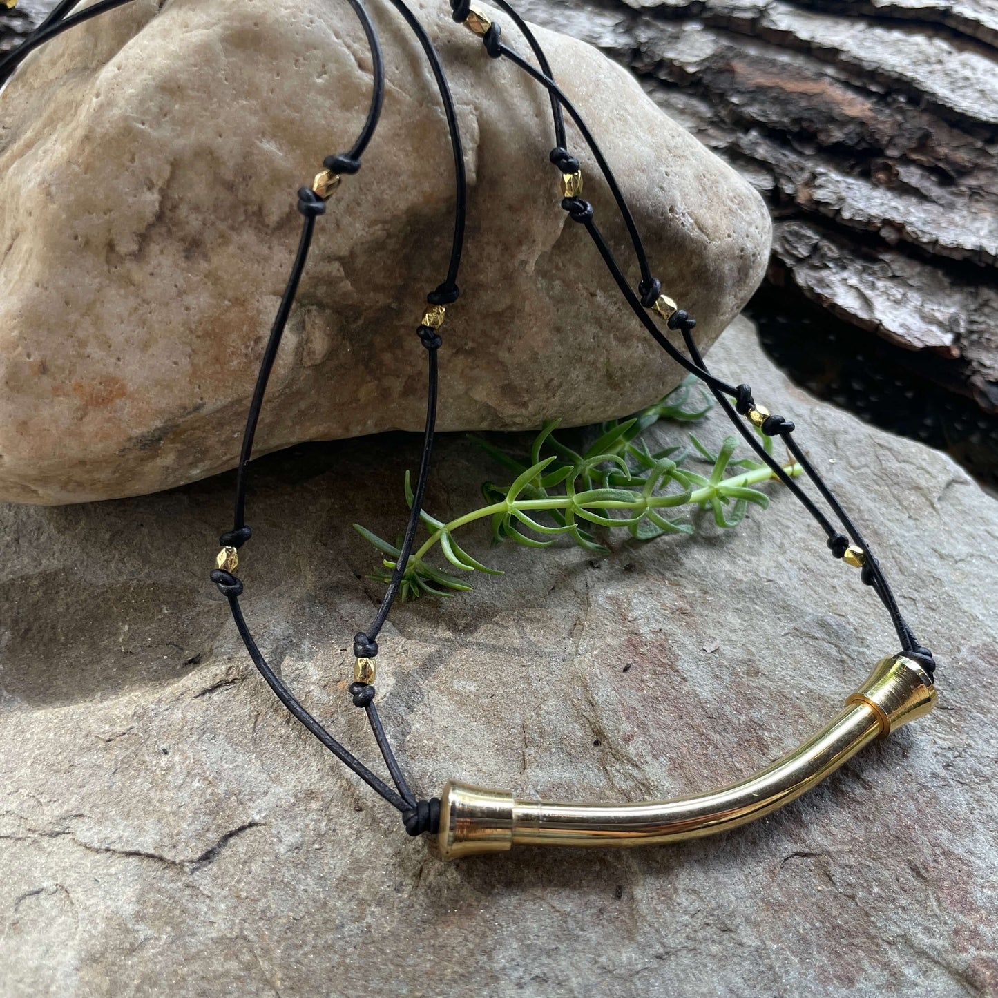 Brass bar necklace on rock